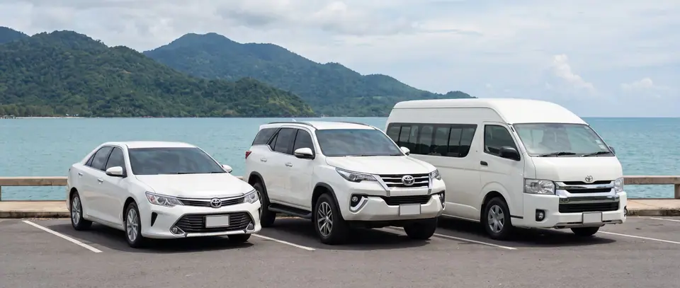 꼬창이 보이는 뜨랏 해안에 서 있는 세단, SUV, 밴